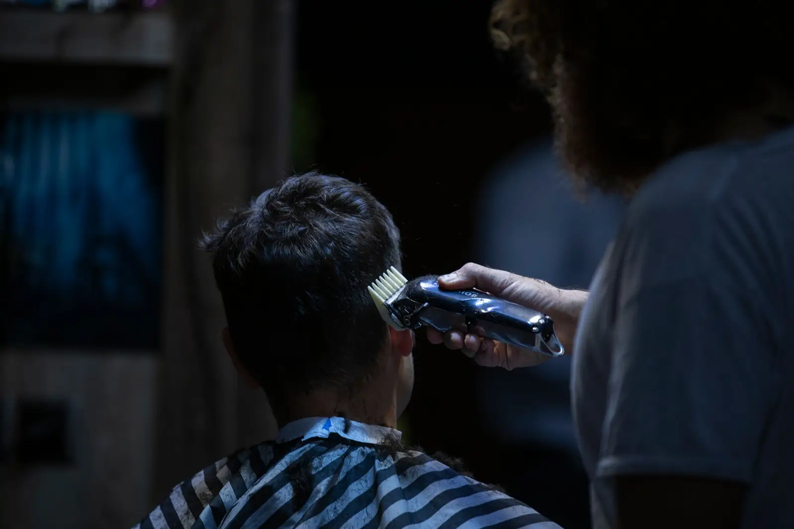 Barber using clippers on a client in a cape