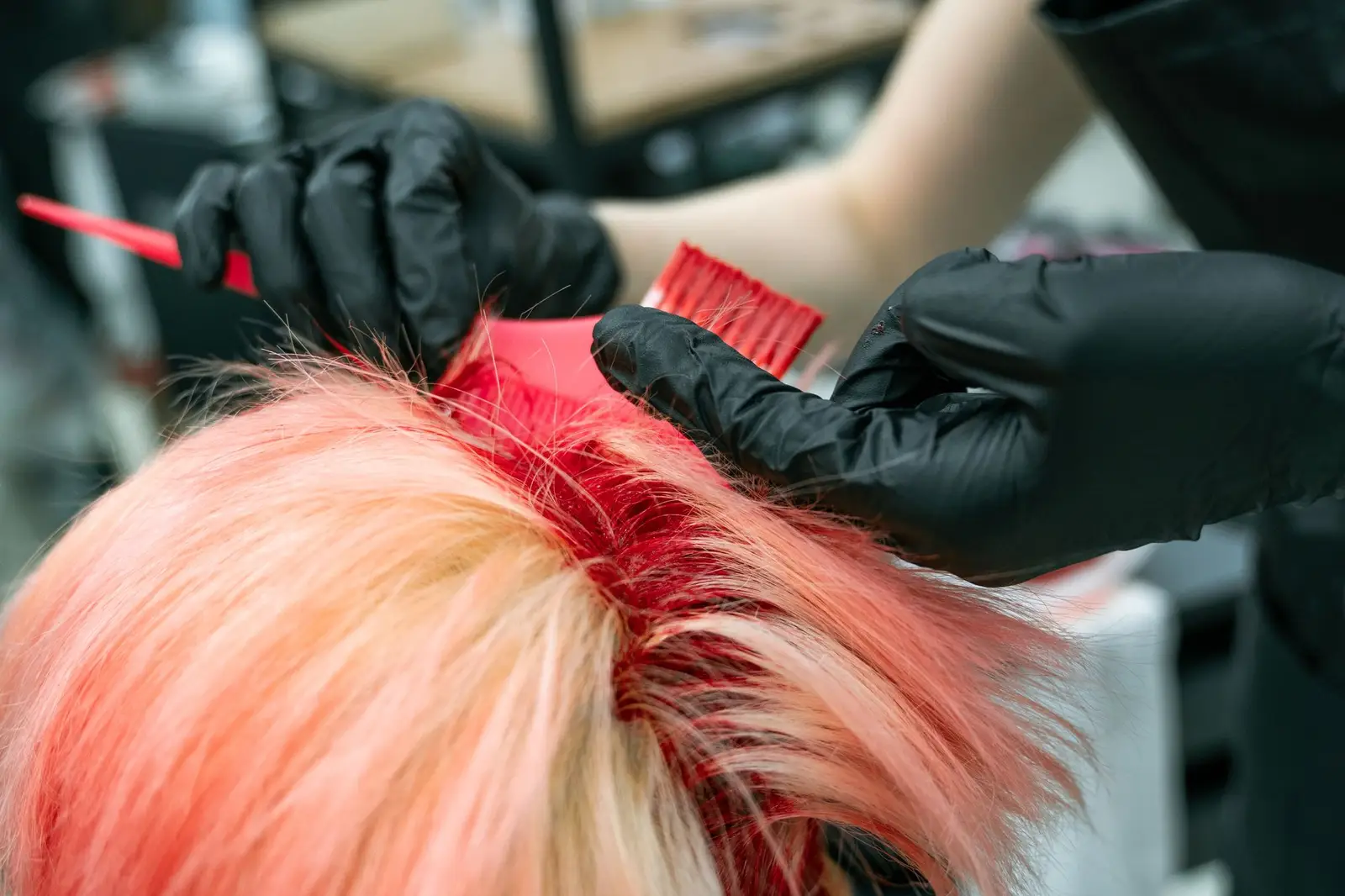 Gloved hands applying pink and blonde hair colour