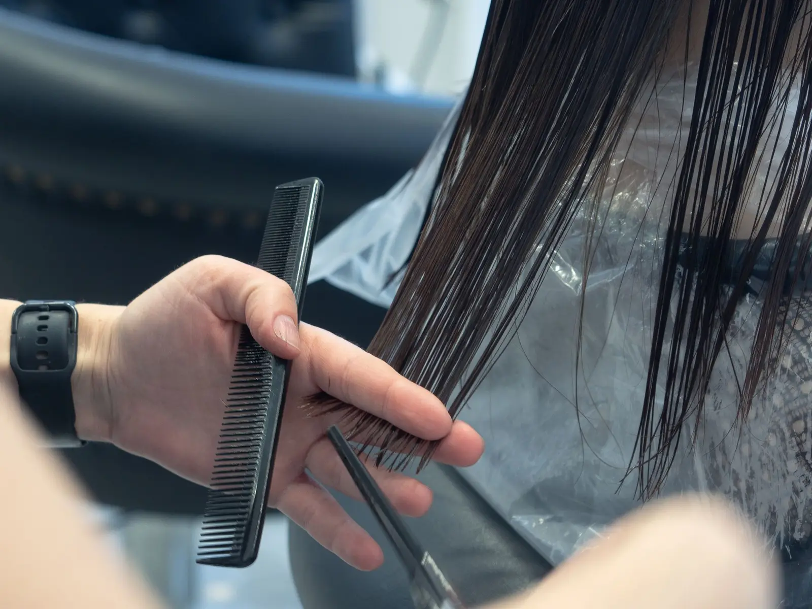 Stylist combing and sectioning long dark hair