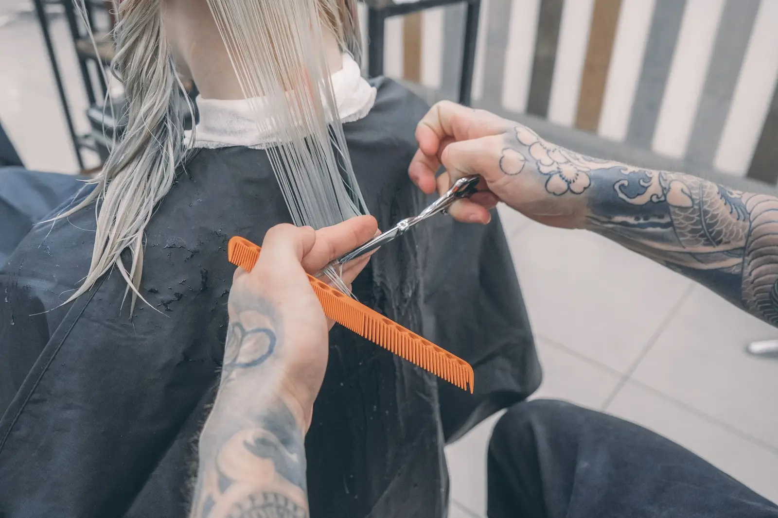Stylist cutting wet hair with scissors and comb